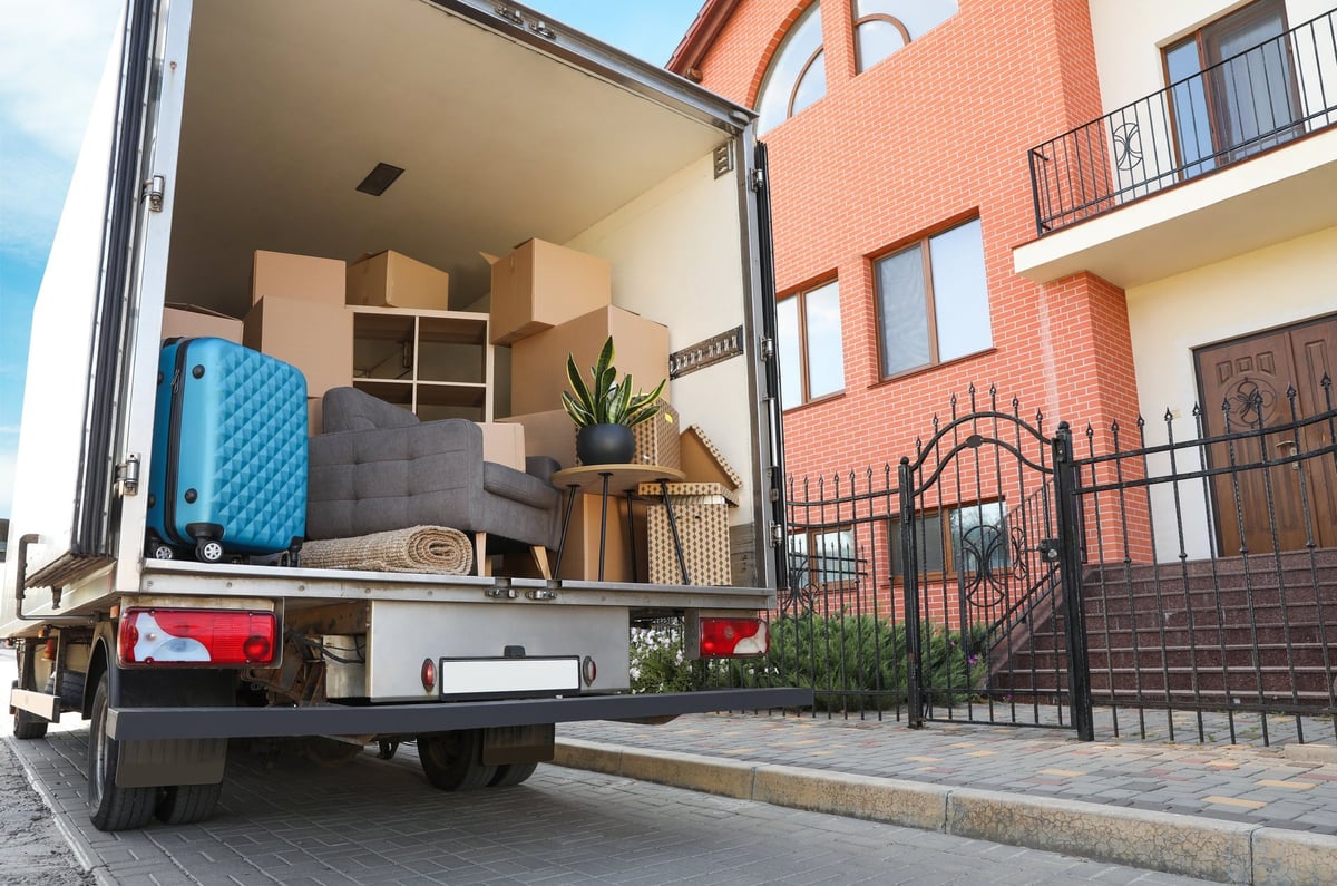 Van filled with moving boxes and furniture parked near a house