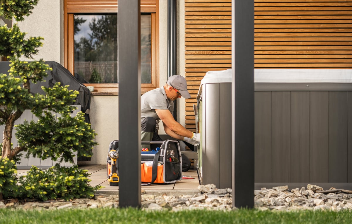 Technician working on a hot tub in a backyard